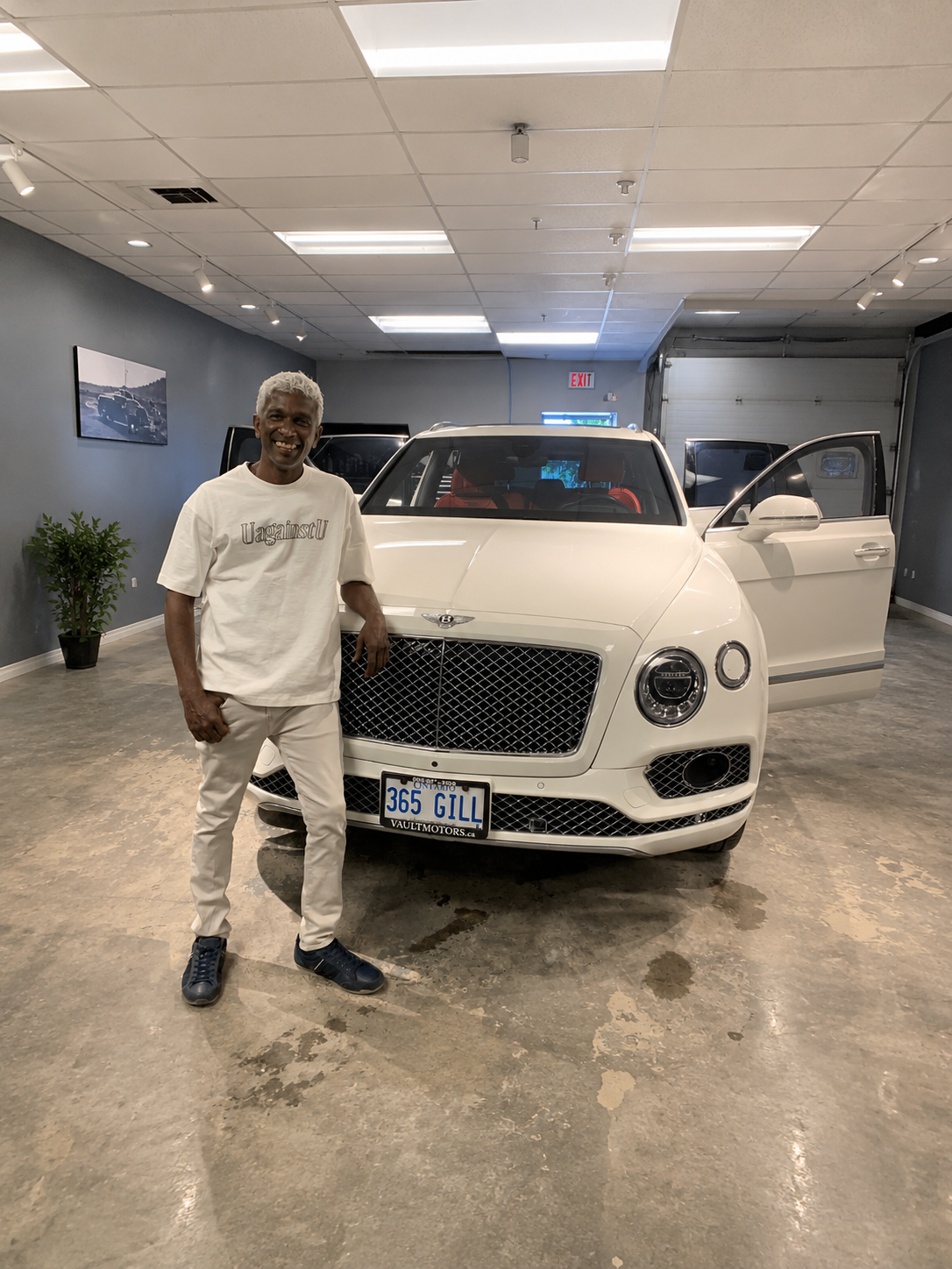 Dinesh standing beside a luxury SUV detailed at Double M Auto Detailers